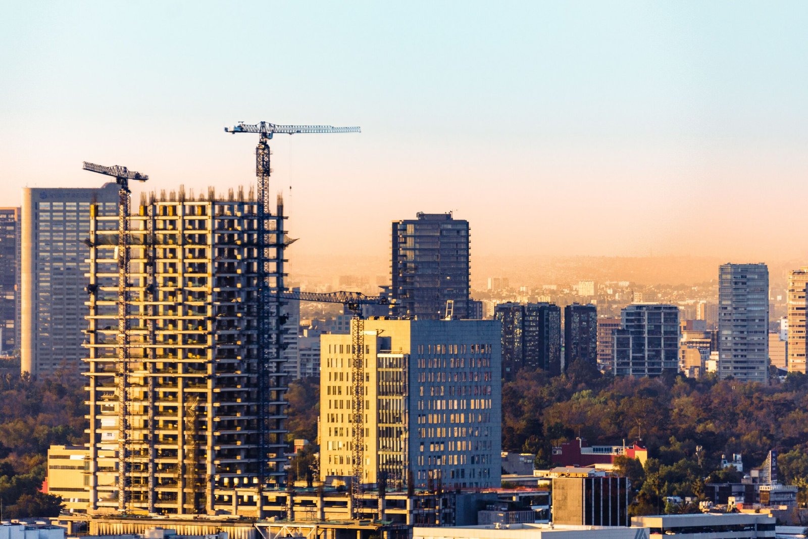 pexels-photo-15937637-15937637 Aerial view of construction cranes and skyscrapers in Ciudad de México at sunset.